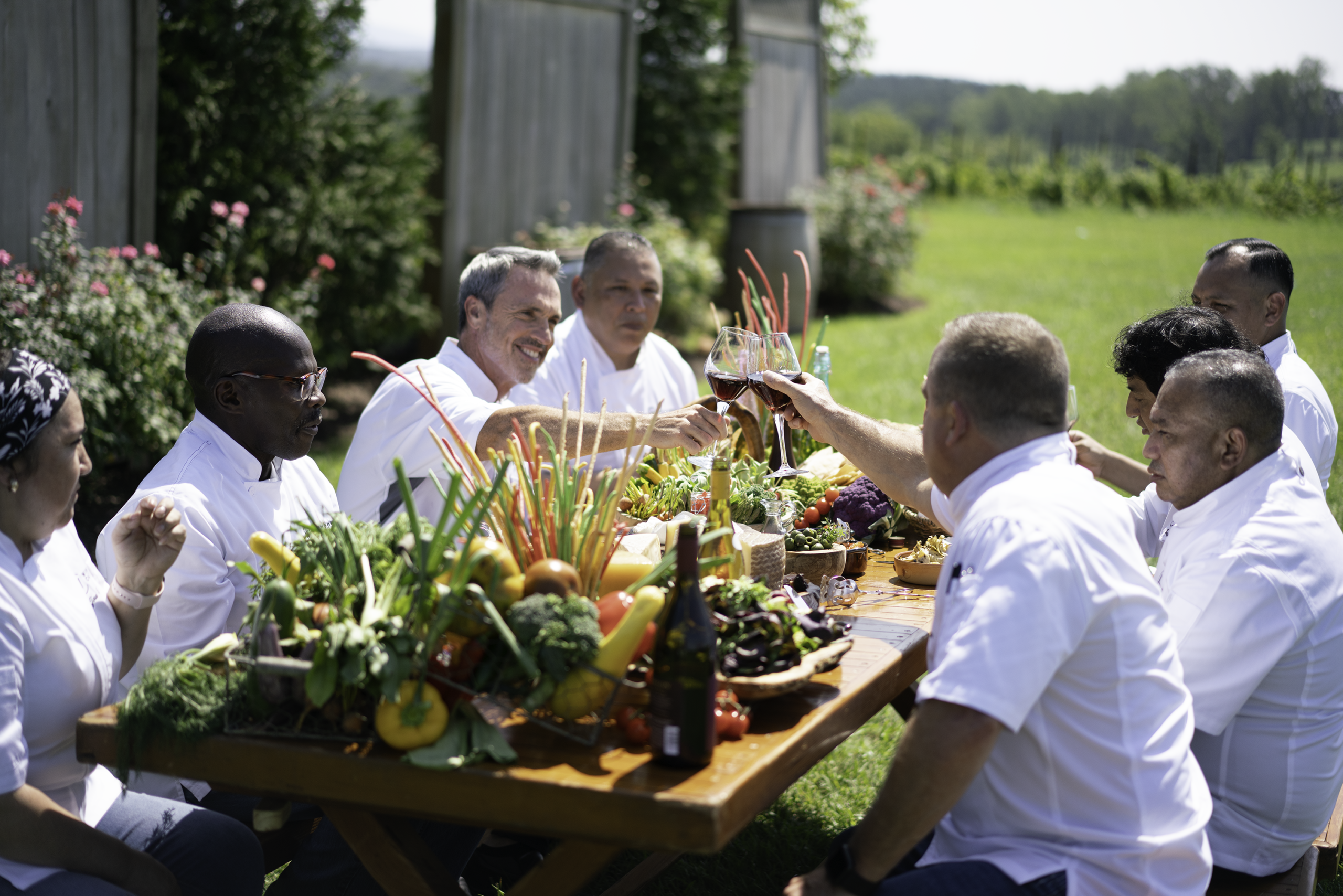 Group of windows catering team members cheersing classes of wine around large grazing table
