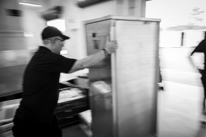A man in a black shirt moves a refrigerator.