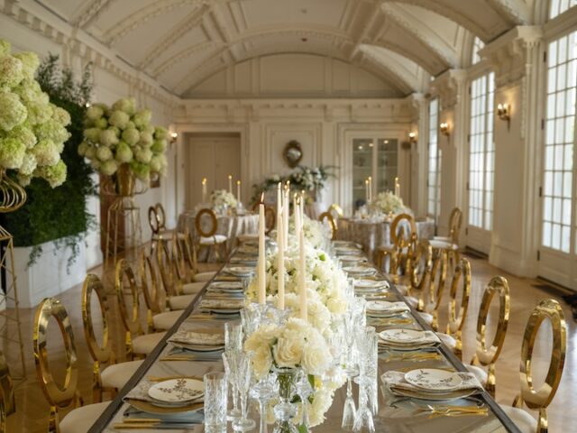 A long table with gold chairs and white flowers set for an elegant event.