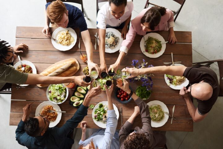 Group of people clinking glasses over a table of food